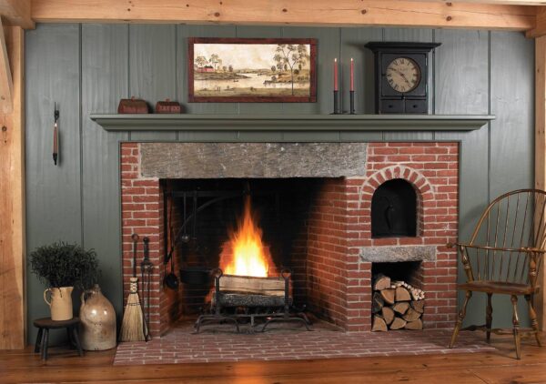 A glowing fire in a huge brick fireplace with big granite lintel stone and beehive oven