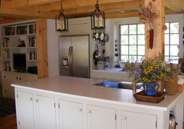 Antique kitchen with white cabinets and timbered ceiling.